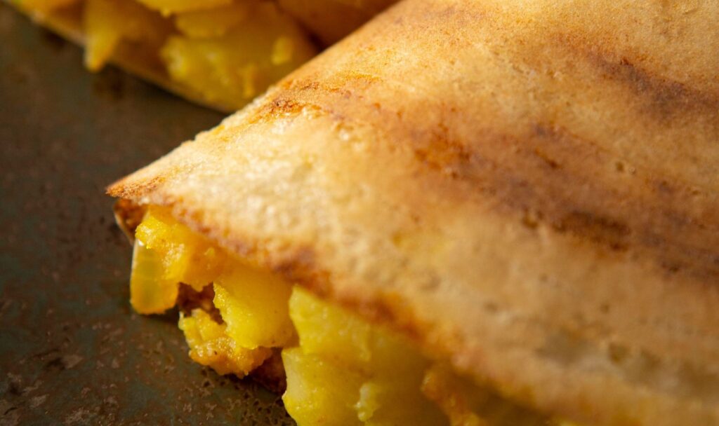 "Crispy golden masala dosa served with spiced potato filling, coconut chutney, and sambar – a classic South Indian delicacy from Vijamma’s Recipes, rich in tradition and authentic flavors.